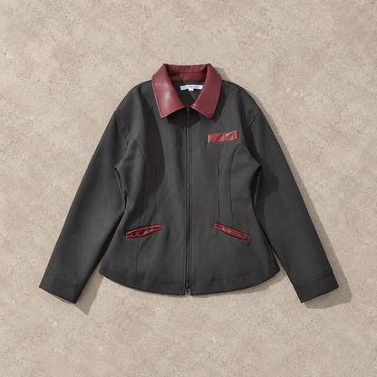 Veste courte gris foncé à col contrastant, vue de face sur fond pierre